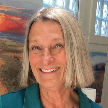 Smiling elderly woman with gray hair in a teal shirt.