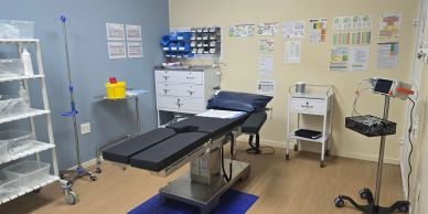 An empty medical examination room with equipment and an examination table.