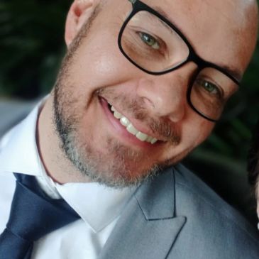 Smiling bald man in glasses and suit.