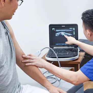 Doctor performing ultrasound on patient's arm.