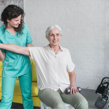 Caregiver assists elderly woman with arm exercise.