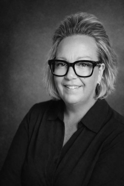 Black and white portrait of a smiling woman with glasses.