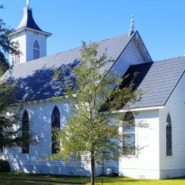 White church building with a small tree in front. Church of the Epiphany. 1870s White frame building