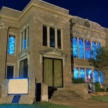 Historic building with stained glass windows illuminated at night. Early 1900s brick building.