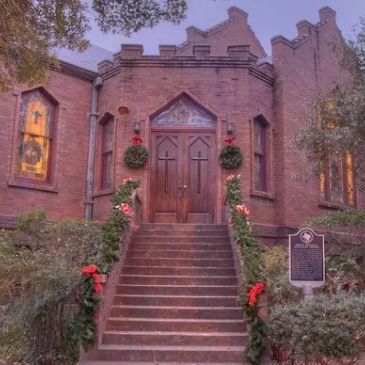 Brick church decorated with greenery and red bows. Early 1900s brick building.