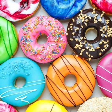 Colorful assorted donuts with various toppings arranged closely together.