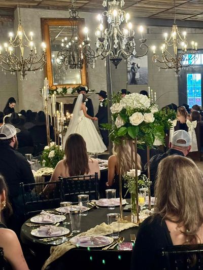 Elegant indoor wedding ceremony with chandeliers and floral decorations.