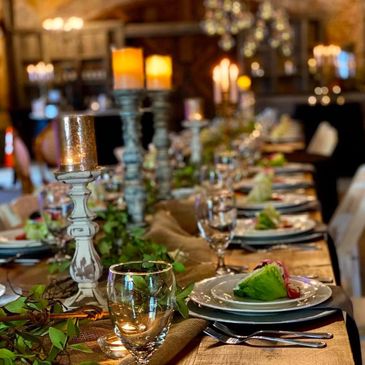 Elegant dining table set with candles and fresh salad plates for a formal event.