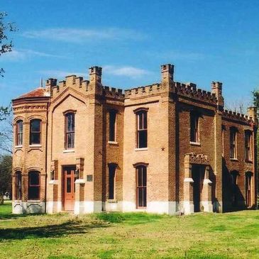 Historic brick building with castle-like crenellations under a clear blue sky.