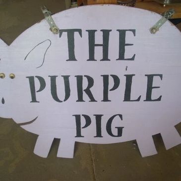 A pig-shaped sign that reads 'The Purple Pig'.