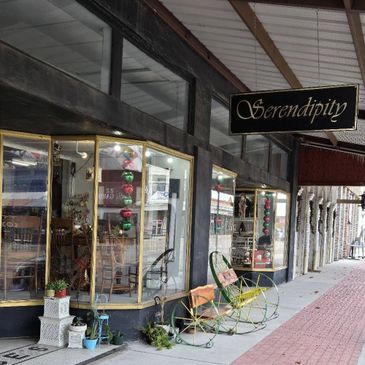 Charming vintage storefront with decorative chairs and plants outside.