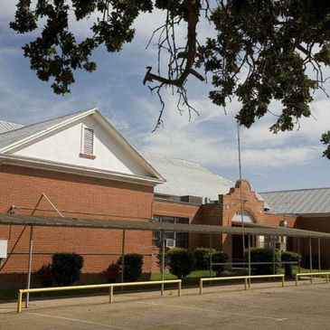 Front view of a brick school building under a partly cloudy sky.