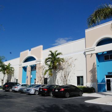 Modern white and blue commercial building with cars parked outside.