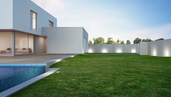 A modern white house with a swimming pool and spacious green lawn.