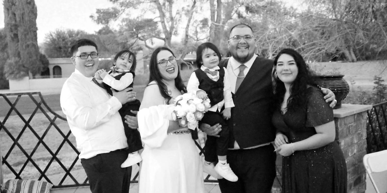 A joyful family portrait at a wedding with two young children.