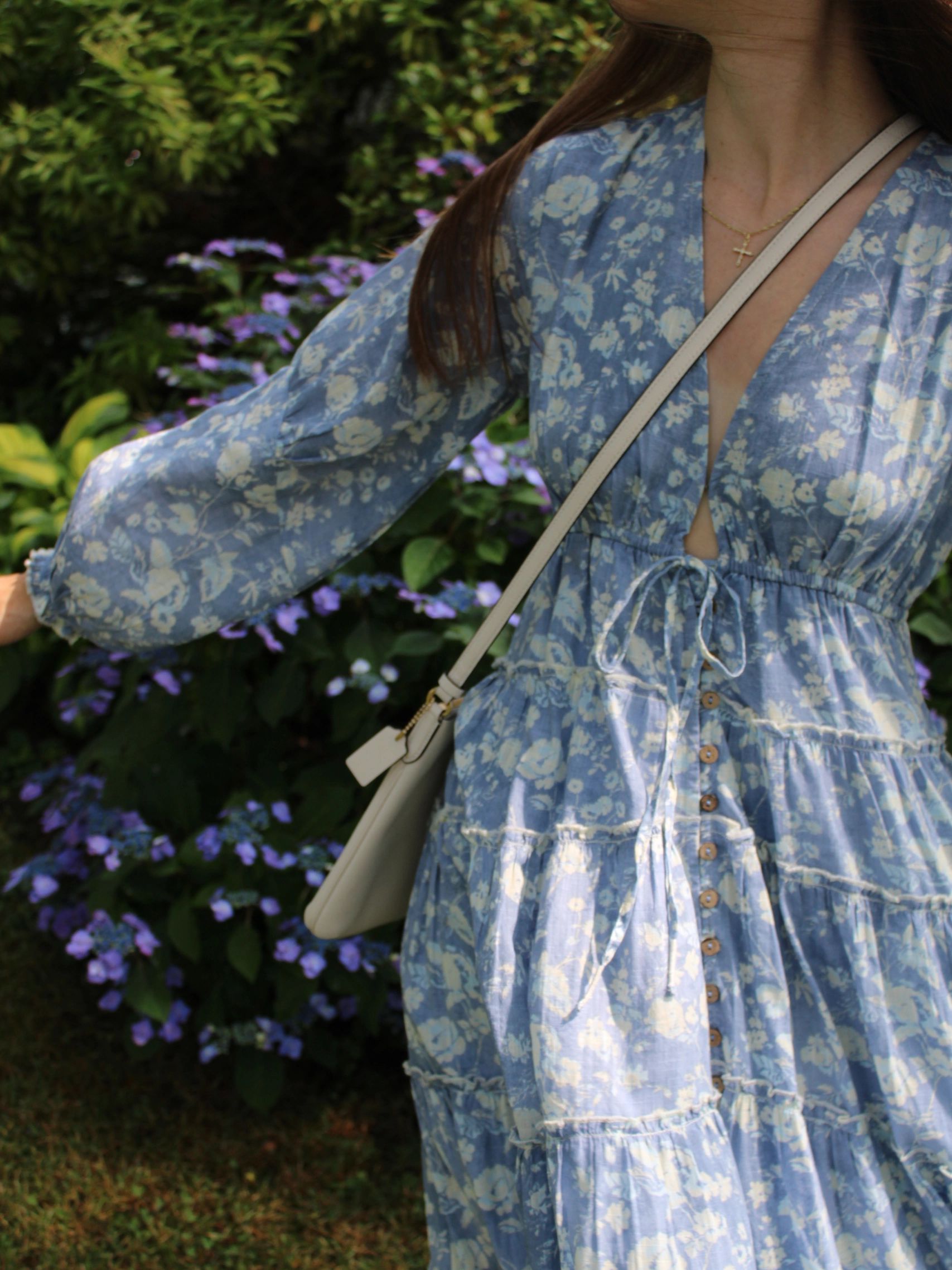 Blue floral dress with buttons and a cross necklace.