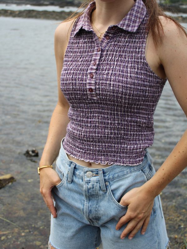 Woman in purple sleeveless top and denim shorts.