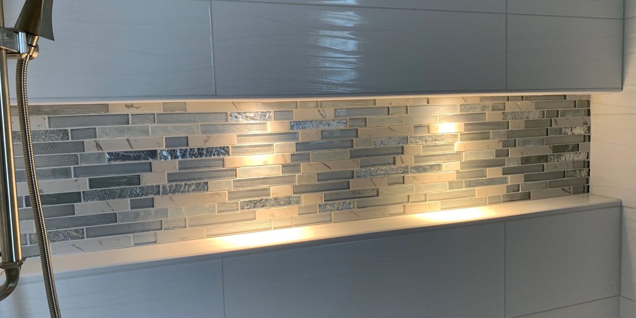Modern bathroom wall with decorative tiles and lighting.