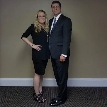 A couple dressed formally posing for a photo indoors.