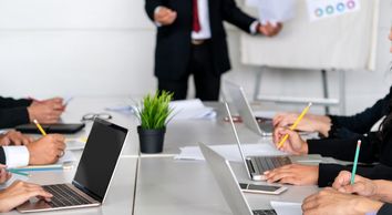 People attending a business meeting with laptops and notes.