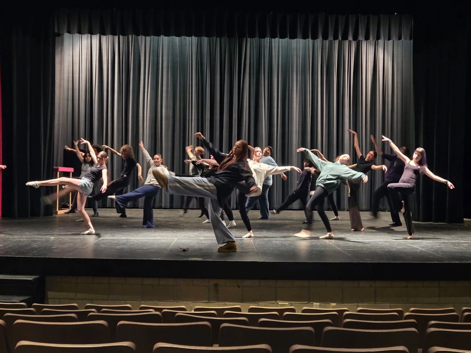 Group of dancers rehearsing a choreographed routine on stage.
