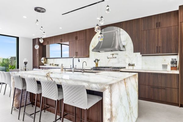 Modern kitchen with marble island and wooden cabinetry.