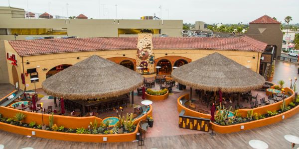 Outdoor seating area with two large thatched roofs.