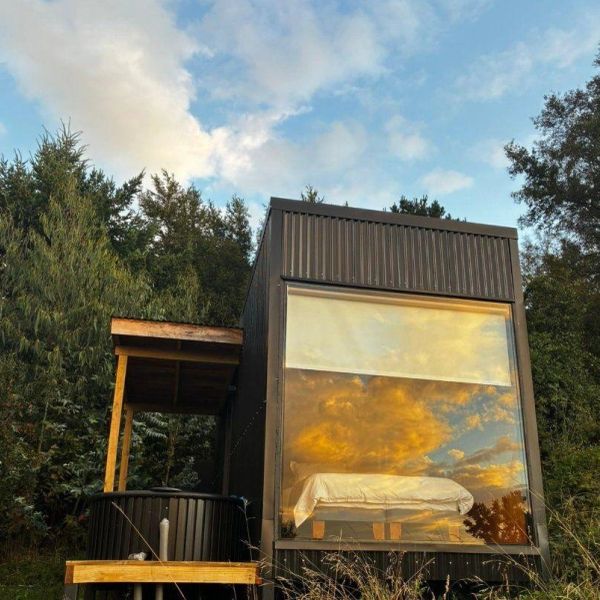 Casa moderna con gran ventana reflejando el cielo al atardecer.