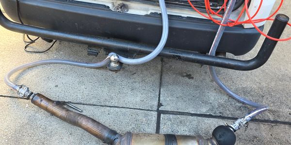 A car exhaust system connected to hoses on a driveway.