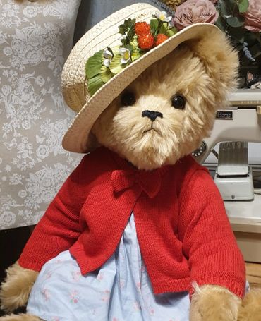 Handmade mohair teddy bear ready for summer in a cotton frock and cardigan; straw hat; strawberries.
