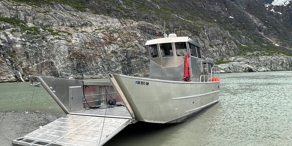 Aluminum landing craft boat with ramp on a mountain lake shore.