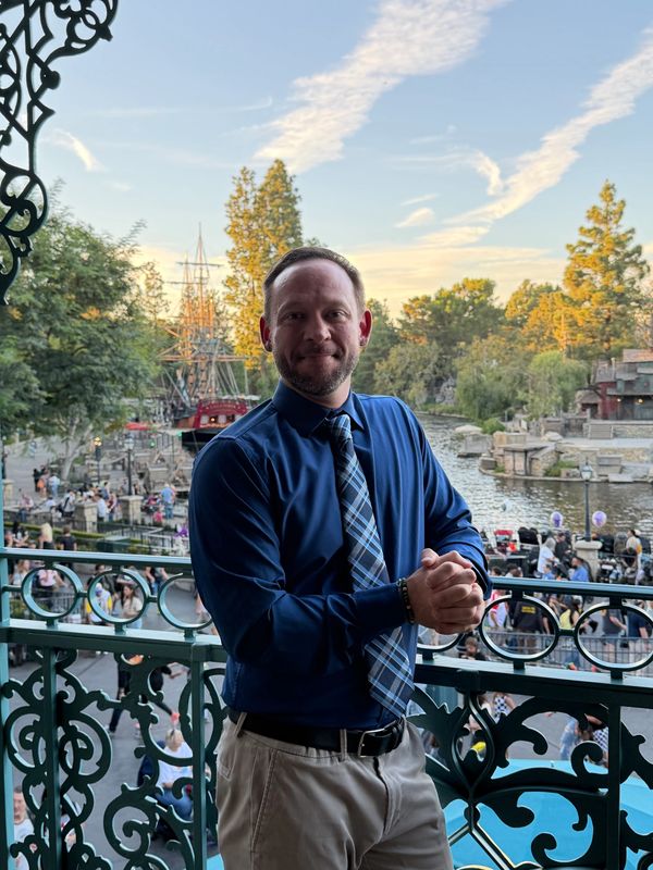 Fox leaning against the railing at 21 Royal overlooking sections of Disneyland Park.