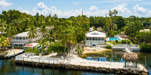 Waterfront tropical homes with palm trees and a sandy beach area.