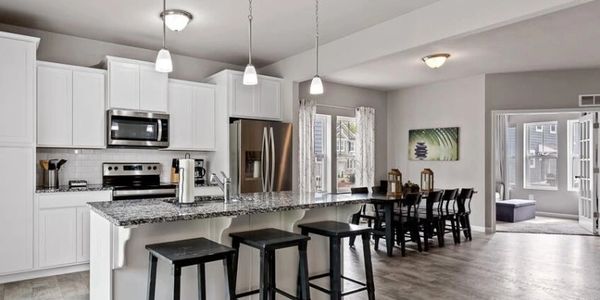 Modern kitchen with white cabinets and black bar stools.