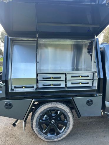 Open truck compartment with metal storage drawers.