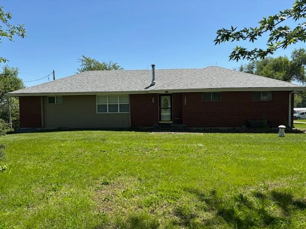 Red brick ranch house with a grey shingle roof.