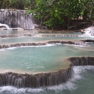 Tiered turquoise waterfall pools surrounded by lush green forest.