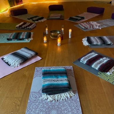 Yoga mats arranged in a circle with folded blankets and candles in the center.