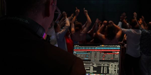 DJ playing music at a party with people dancing.