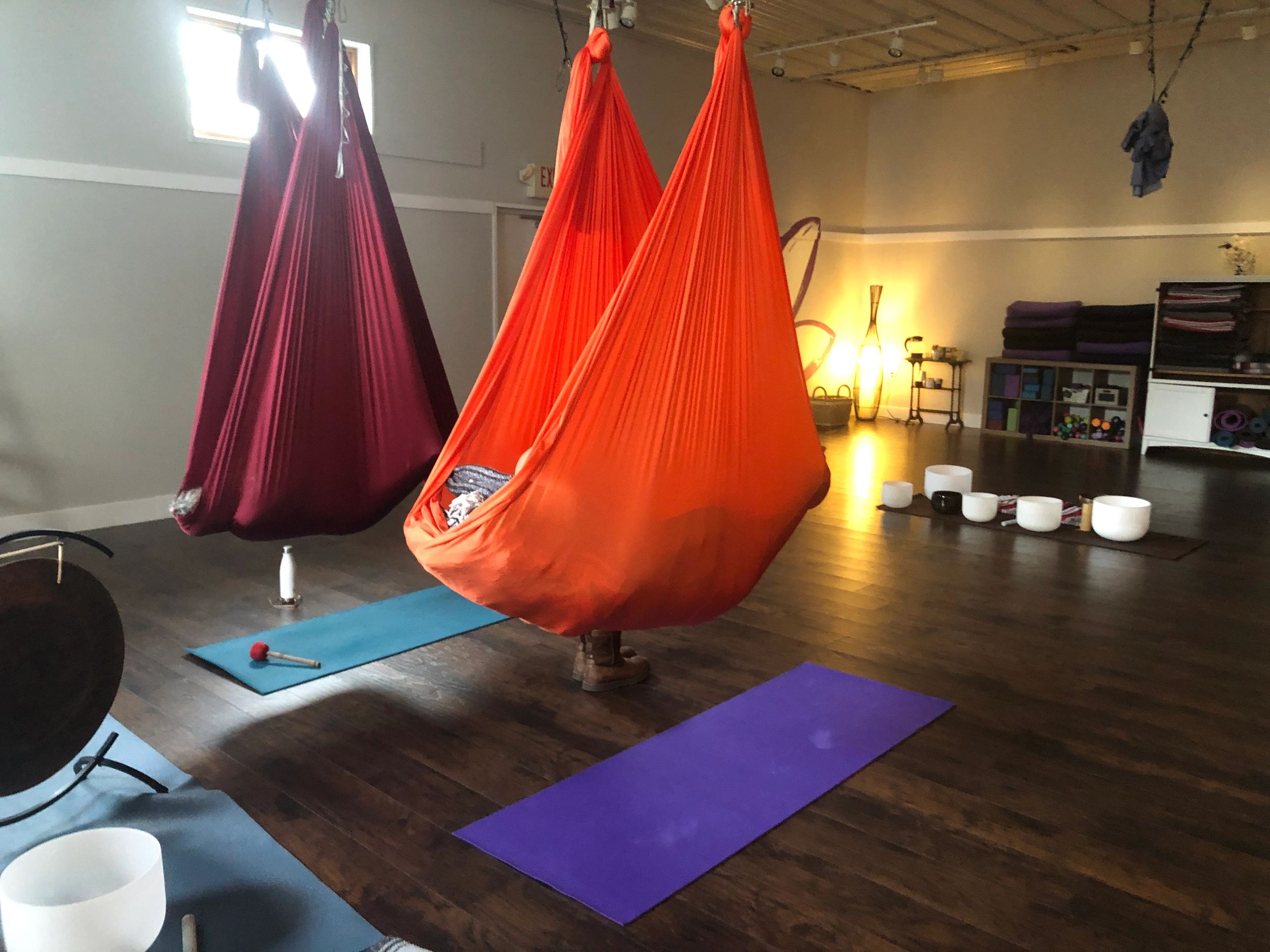 Aerial yoga hammocks and yoga mats in a tranquil studio with soft lighting.