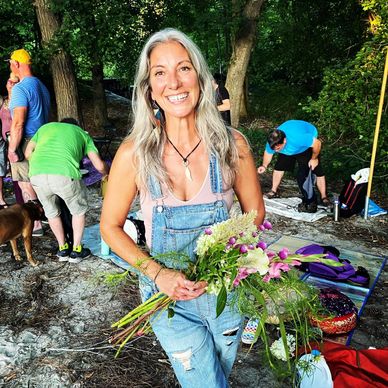 Smiling woman holding a bouquet of flowers in a park setting.