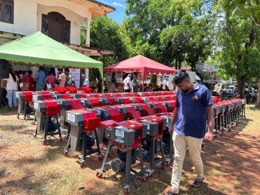 Rows of red machines displayed outdoors with people and tents nearby.