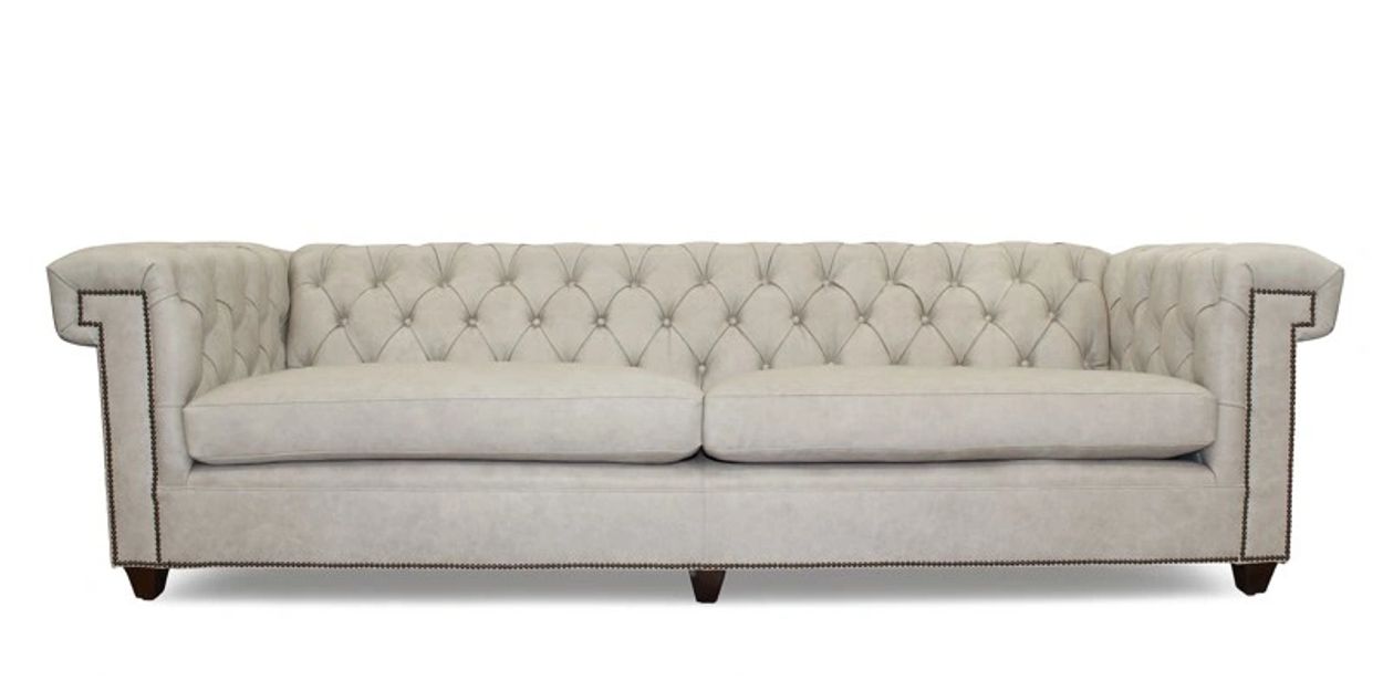 Elegant beige tufted sofa with nailhead trim and plush cushions.