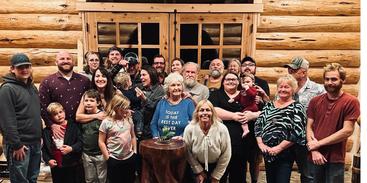 A large multi-generation family posing together inside a cozy log cabin.