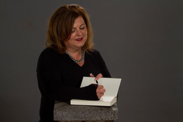 Woman signing a book with a pen.