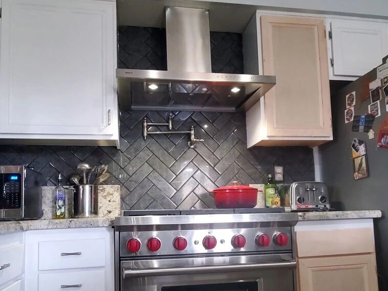 Kitchen with a herringbone tile backsplash, range hood and a Wolf range