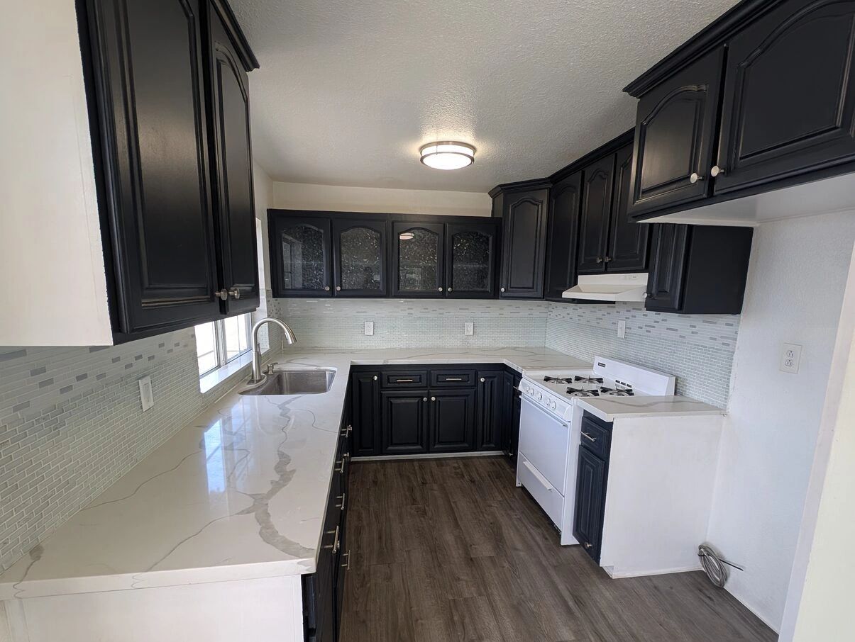 Kitchen with black shaker cabinets, white counters and new plank flooring in Redlands