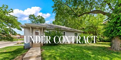 Charming single-story house with "Under Contract" sign on lush green lawn.