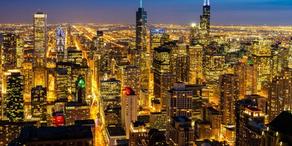 Nighttime cityscape with illuminated skyscrapers and streets.