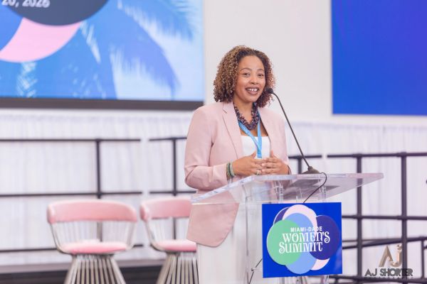 Woman speaking at Miami-Dade Women's Summit podium.